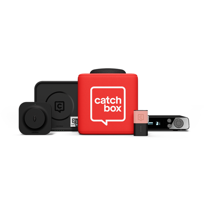 A Catchbox Plus system is displayed, featuring several components. At the center is a large red Cube audience mic with the "Catchbox" logo. Surrounding it are a Cube wireless charger, a Clip presenter mic with a pink jacket, a Clip mic charging dock and a Hub receiver.